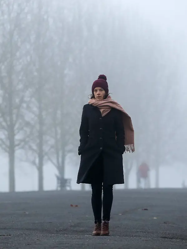 November 27, 2020, London, United Kingdom: A woman wrapped up warm walk on the street on a foggy and cold morning in Lon