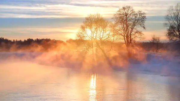 Sonnenaufgang über dampfenden Wasser in Winter-Landschaft mit Schnee und Eis an einem Fluss